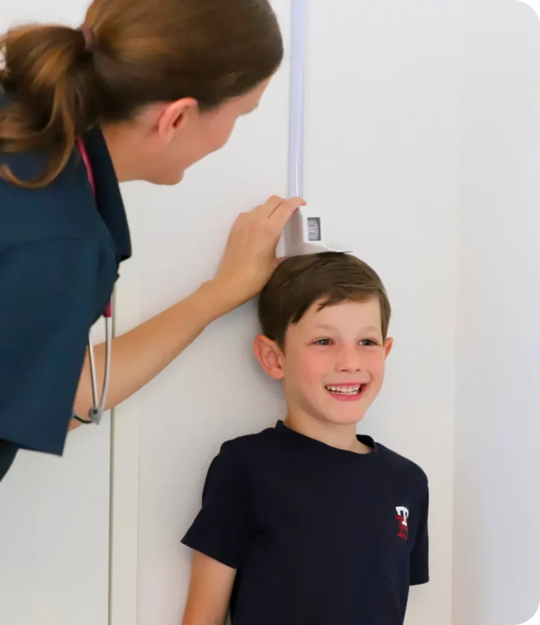 Ärztin misst die Körpergröße eines lachenden Jungen