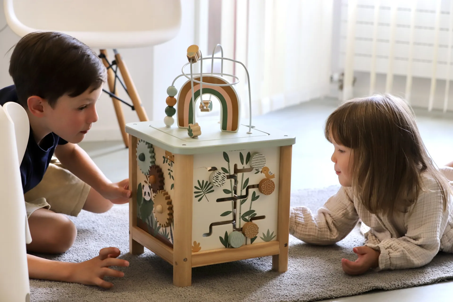 Zwei Kinder spielen im Wartezimmer mit einem Motorikwürfel aus Holz