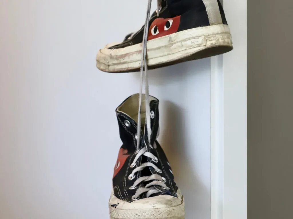 Ein Paar Turnschuhe hängt an den Schnürsenkeln an einer Tür