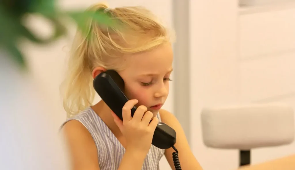 Mädchen telefoniert mit einem Telefonhörer am Empfang